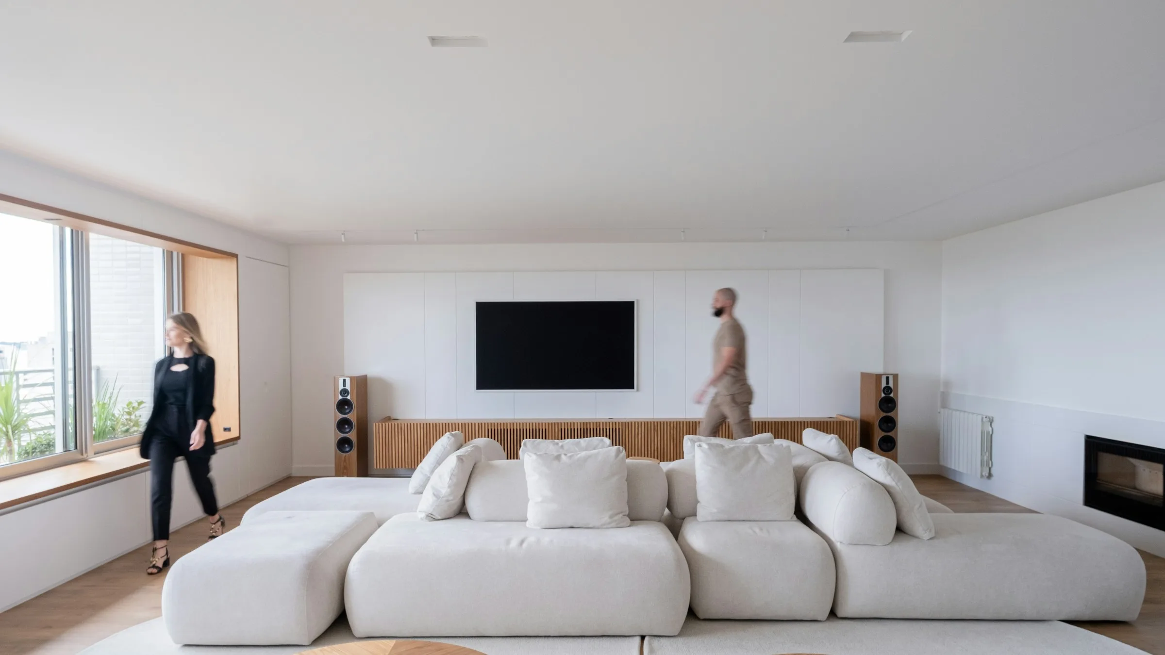 Salón luminoso de una vivienda con un sofá amplio junto a los ventanales