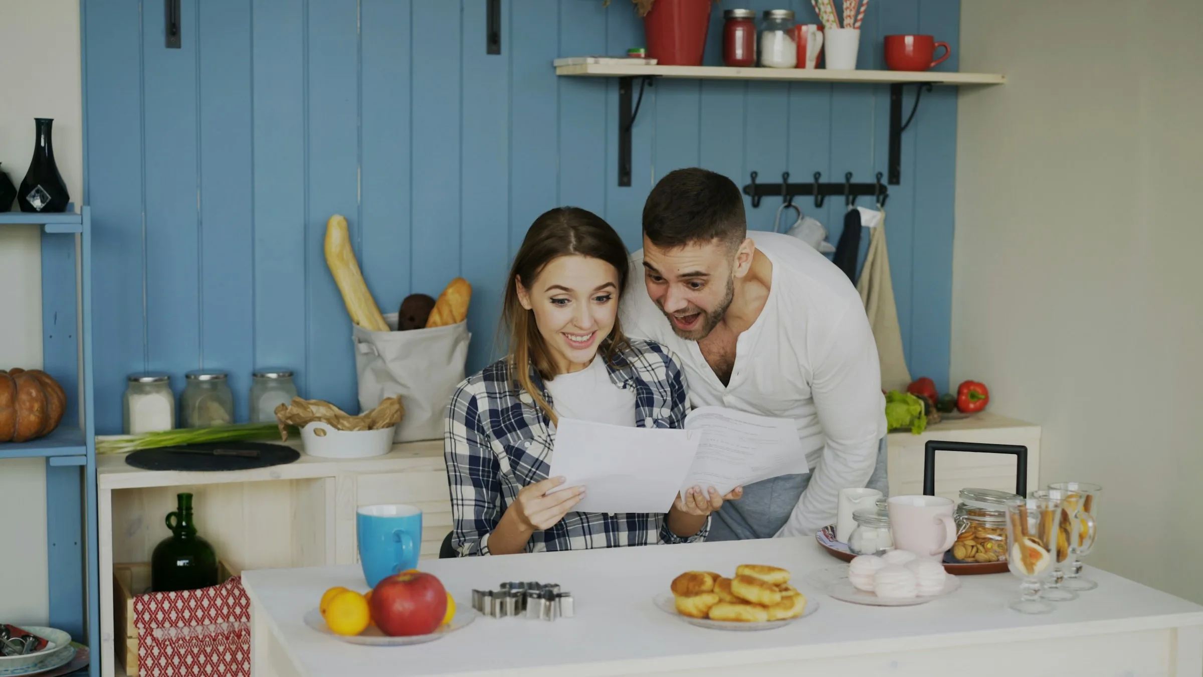 Pareja revisando documentos con un portátil en la cocina de casa