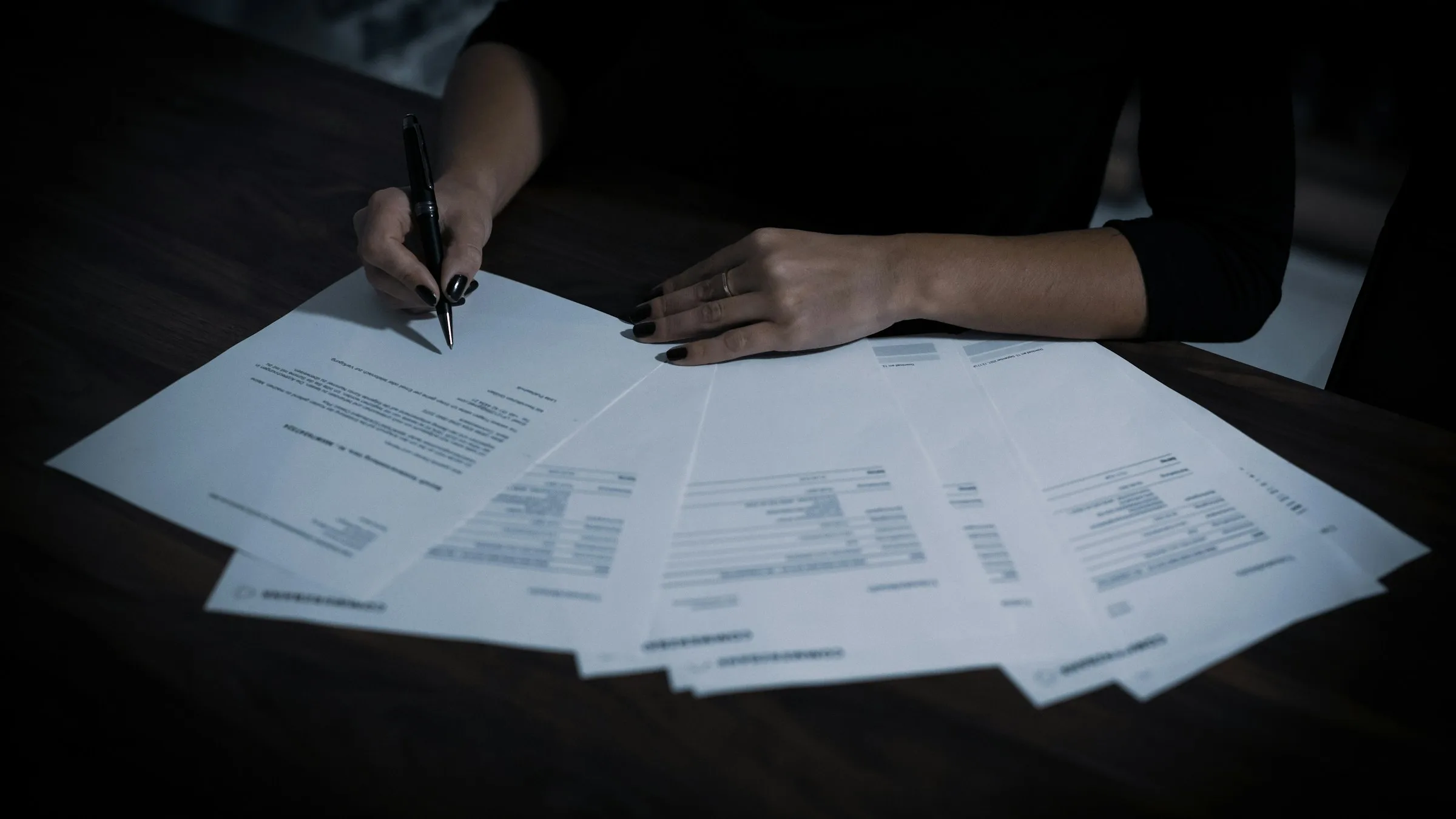 Persona firmando documentación de empresa sobre una mesa