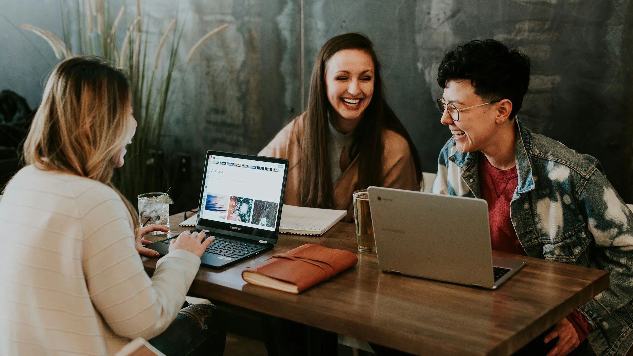 Tres personas conversando alrededor de una mesa con un portátil