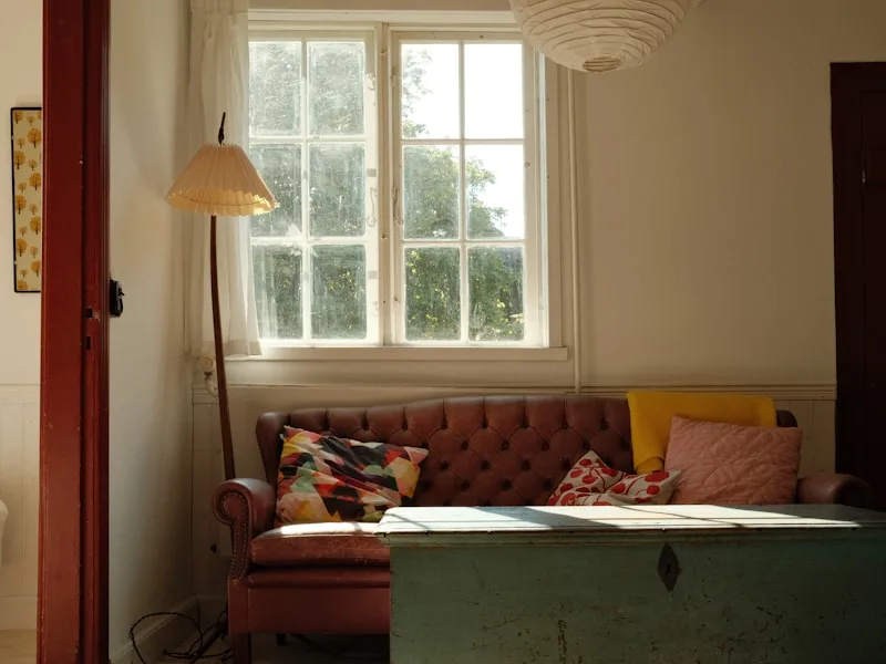 Salón con sofá junto a la ventana y papeles sobre la mesa